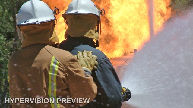 Firefighters Facing Flames Behind a Water Jet