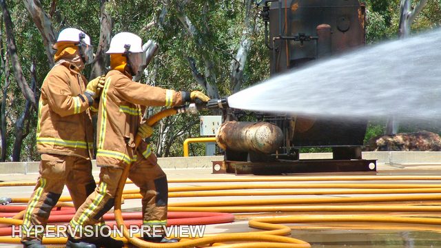 Two Firefighters Directing a Hose Across Coiled Lines