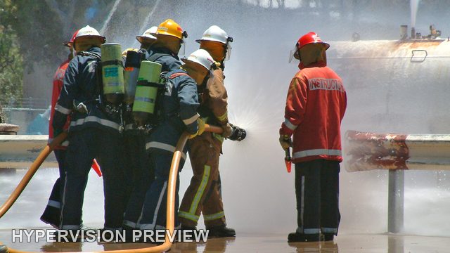 Instructor and Fire Crew Beside a Misty Training Tank