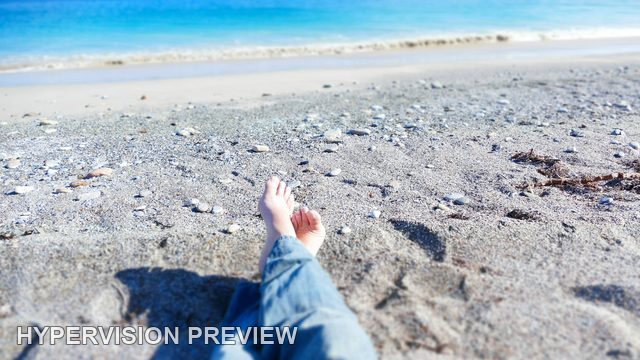Bare Feet Crossed on a Sunny Beach