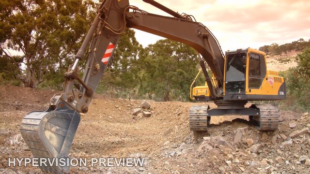 Excavator on Rough Ground Beneath Warm Clouds