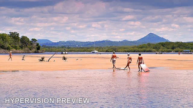 People Wading Across River Shallows