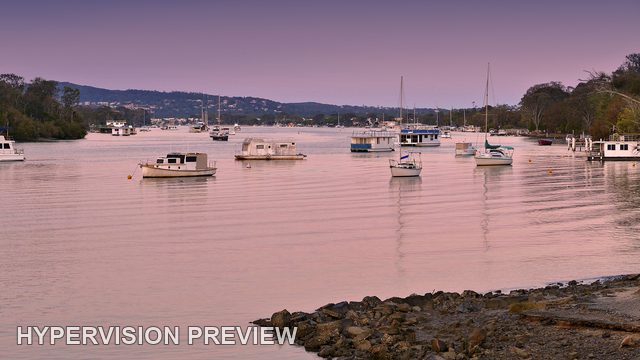 Anchored Boats Beyond a Rocky Riverbank
