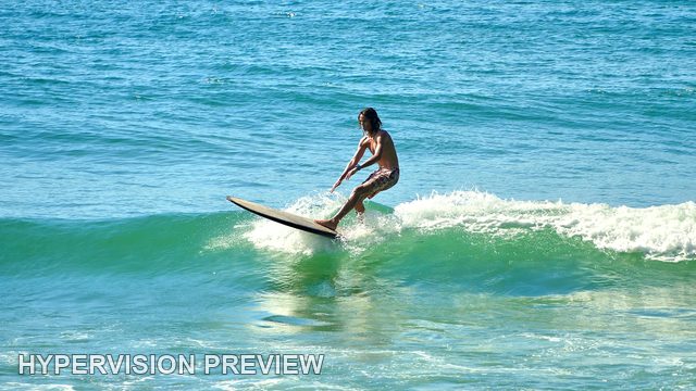 Longboard Rider Gliding Across a Green Wave — Colour