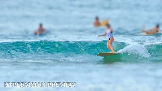 Longboarder with Surfers Waiting Beyond — Selective Focus