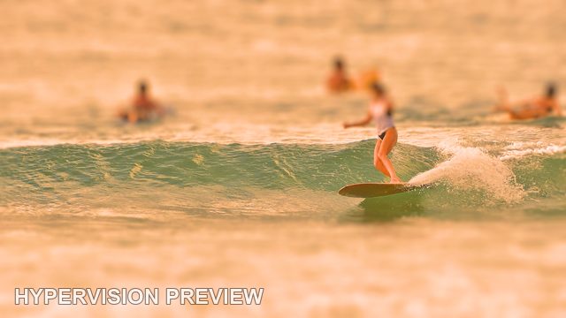 Longboarder with Surfers Waiting Beyond — Warm Colour / Selective Focus