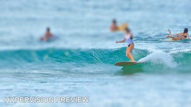 Longboarder with Surfers Waiting Beyond — Selective Focus 01
