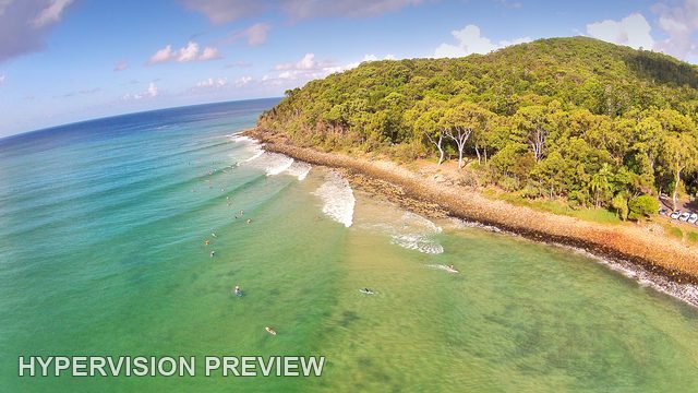 Elevated View of Surfers Beside a Wooded Point — Colour
