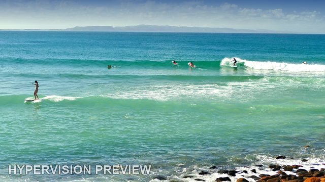 Board Riders Sharing Small Coastal Waves — Colour