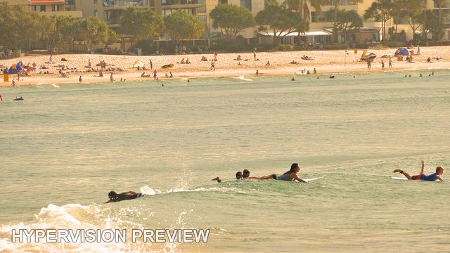 Paddling Surfers with a Busy Beach Beyond — Colour