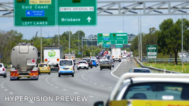 Tanker and Queued Traffic Beneath Cropped Direction Signs
