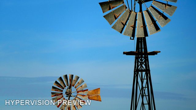 Two Windmills at Different Distances Under Blue Sky