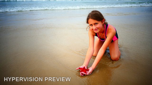 Child Holding a Red Starfish-Shaped Object in the Shallows