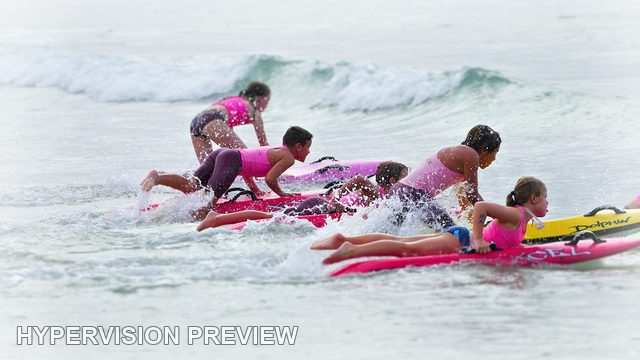 Children Paddling Boards Through Small Waves